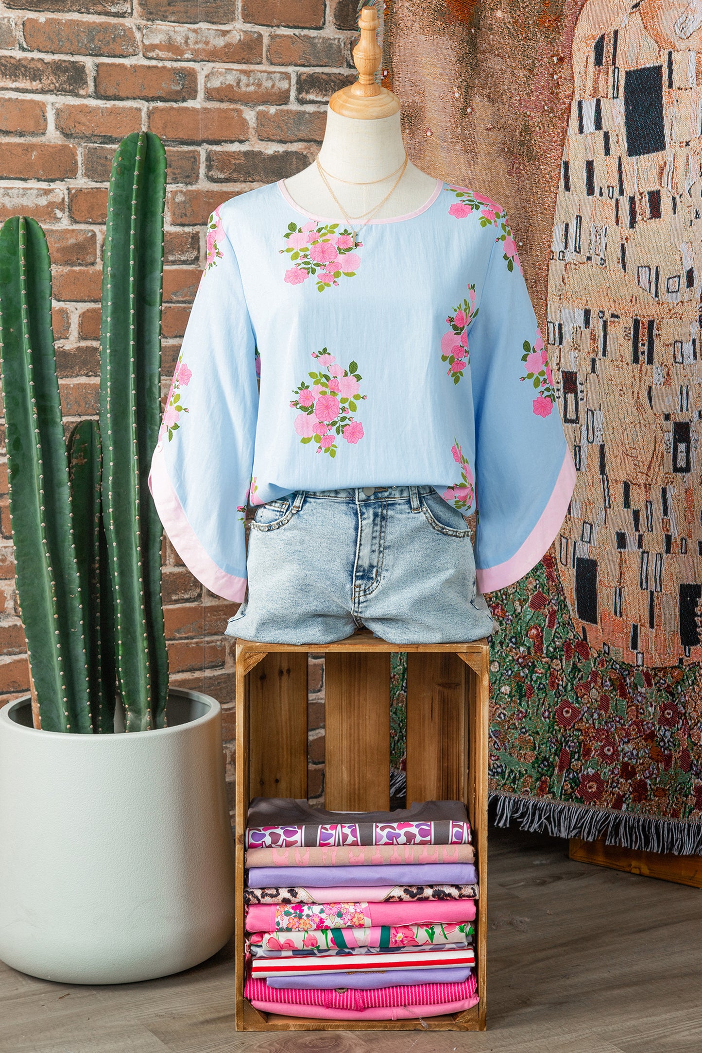 Blusa de manga 3/4 con cuello redondo, botones en los puños y estampado floral azul cielo