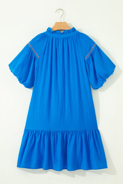 Vestido con bordado de flores azules, cuello dividido, mangas cortas abullonadas y dobladillo con volantes