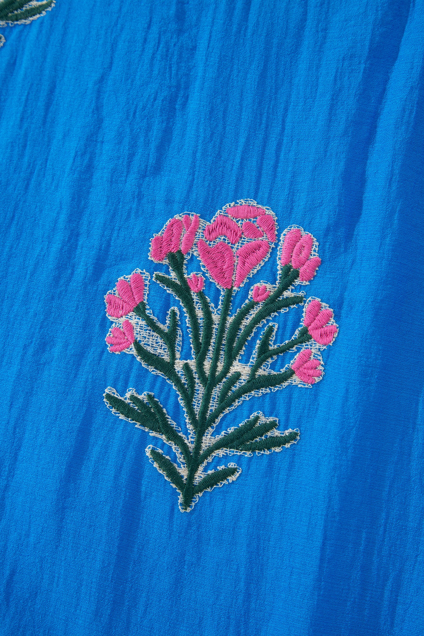 Vestido con bordado de flores azules, cuello dividido, mangas cortas abullonadas y dobladillo con volantes