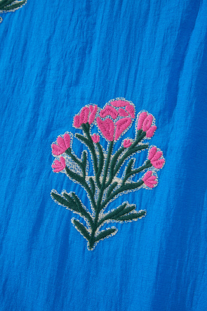 Vestido con bordado de flores azules, cuello dividido, mangas cortas abullonadas y dobladillo con volantes