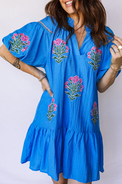 Vestido con bordado de flores azules, cuello dividido, mangas cortas abullonadas y dobladillo con volantes