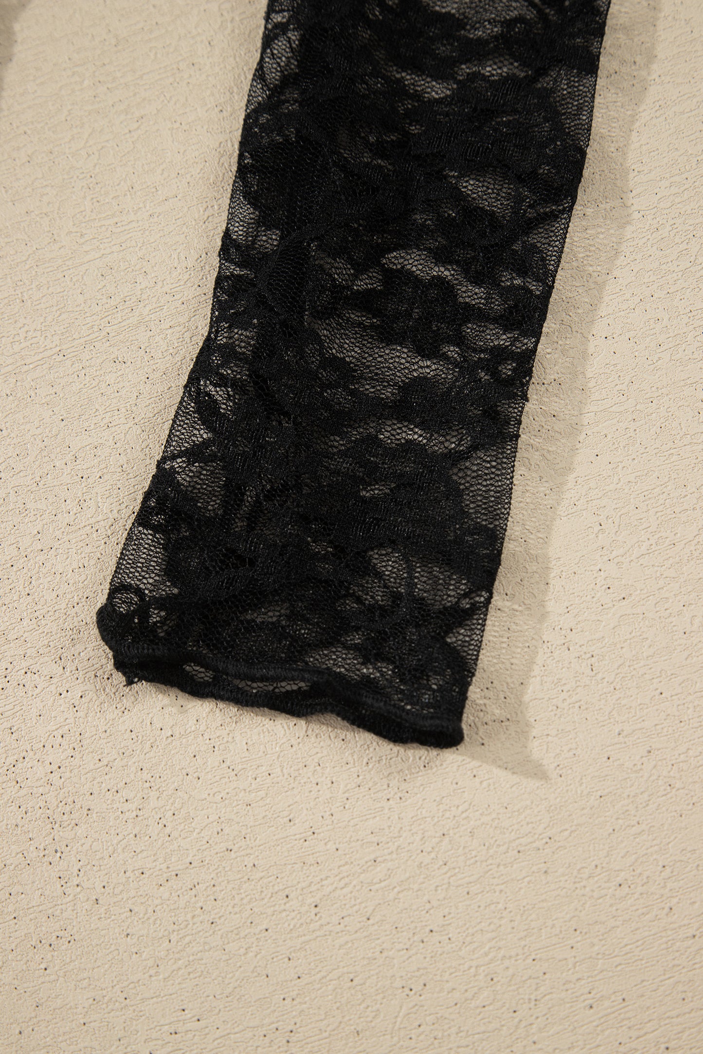 Top de manga larga de encaje floral semitransparente negro con cuello simulado y dobladillo ondulado