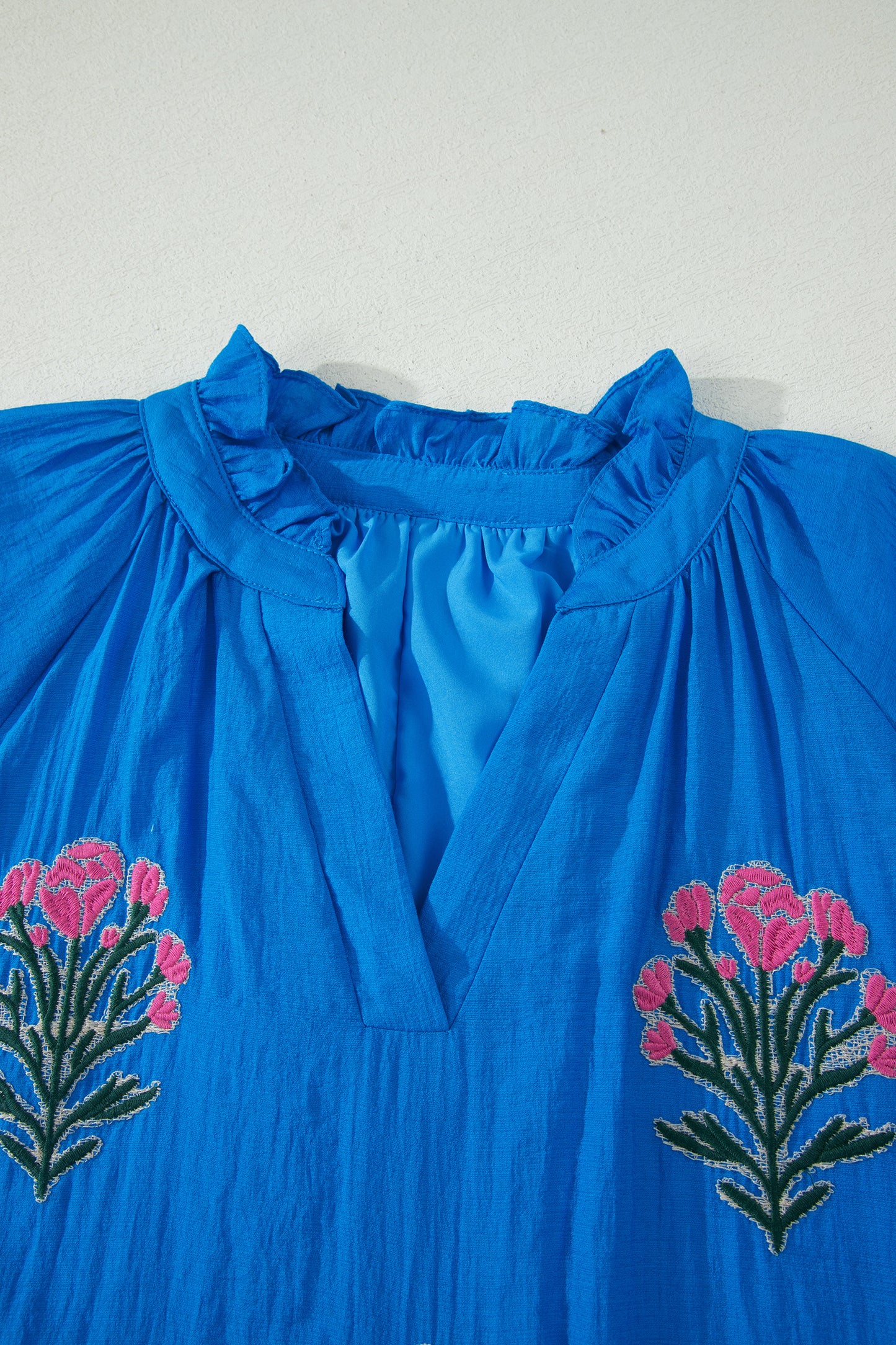 Vestido con bordado de flores azules, cuello dividido, mangas cortas abullonadas y dobladillo con volantes