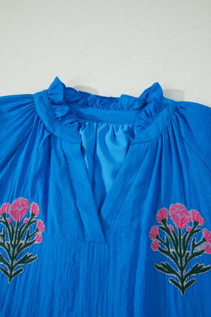 Vestido con bordado de flores azules, cuello dividido, mangas cortas abullonadas y dobladillo con volantes