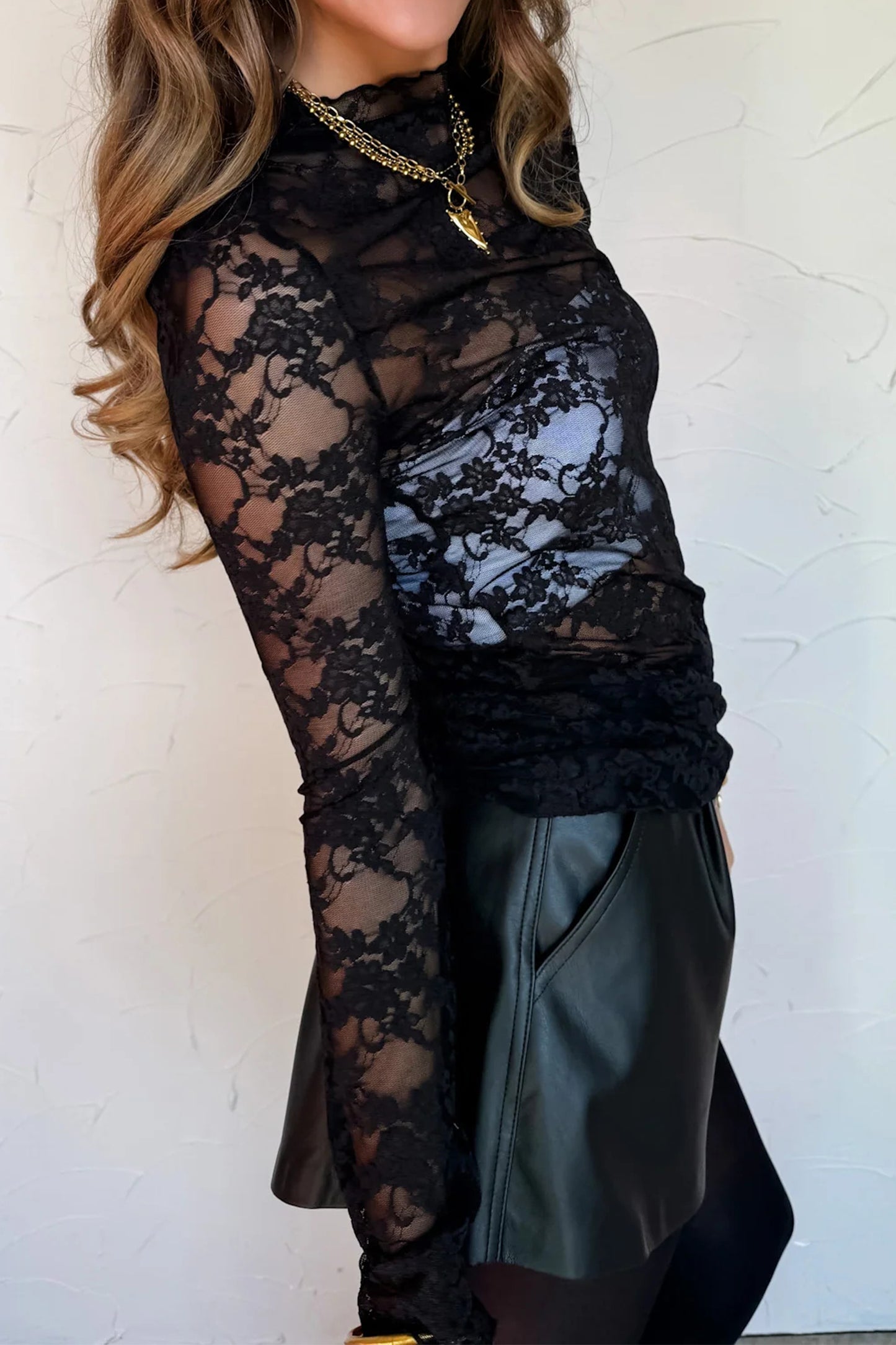 Top de manga larga de encaje floral semitransparente negro con cuello simulado y dobladillo ondulado