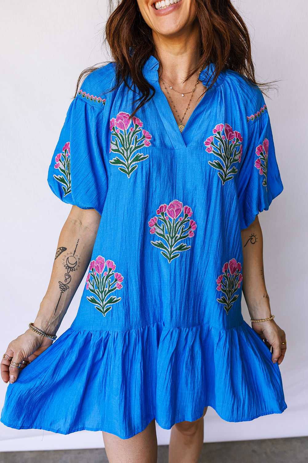 Vestido con bordado de flores azules, cuello dividido, mangas cortas abullonadas y dobladillo con volantes