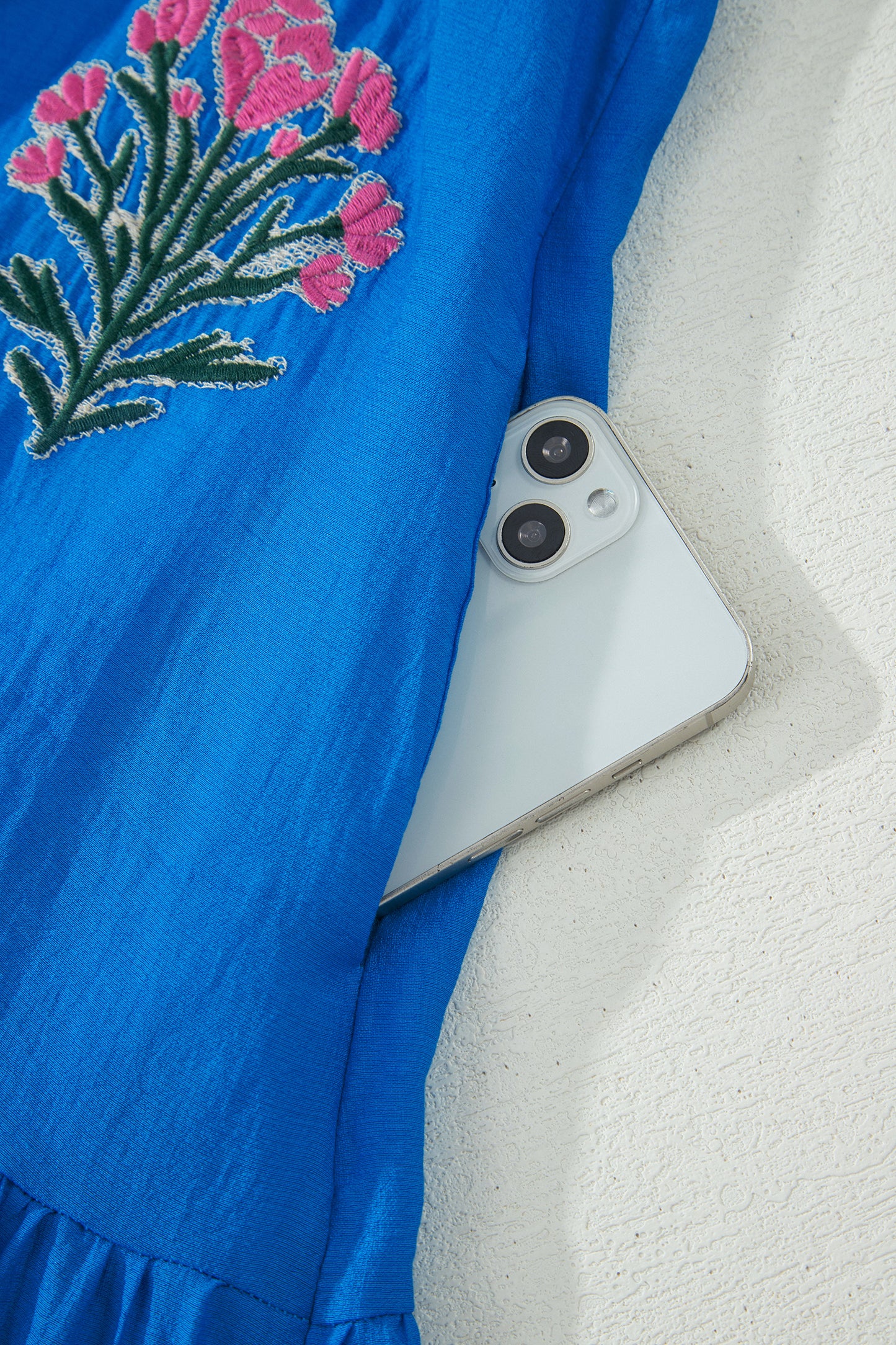 Vestido con bordado de flores azules, cuello dividido, mangas cortas abullonadas y dobladillo con volantes