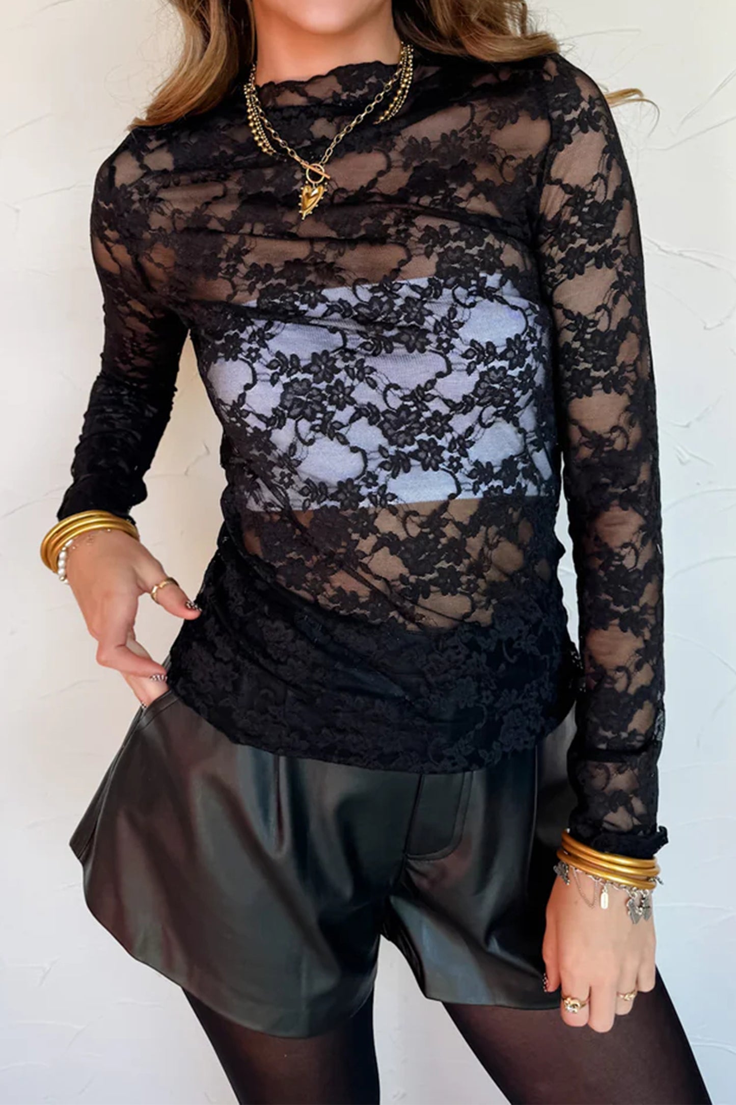 Top de manga larga de encaje floral semitransparente negro con cuello simulado y dobladillo ondulado