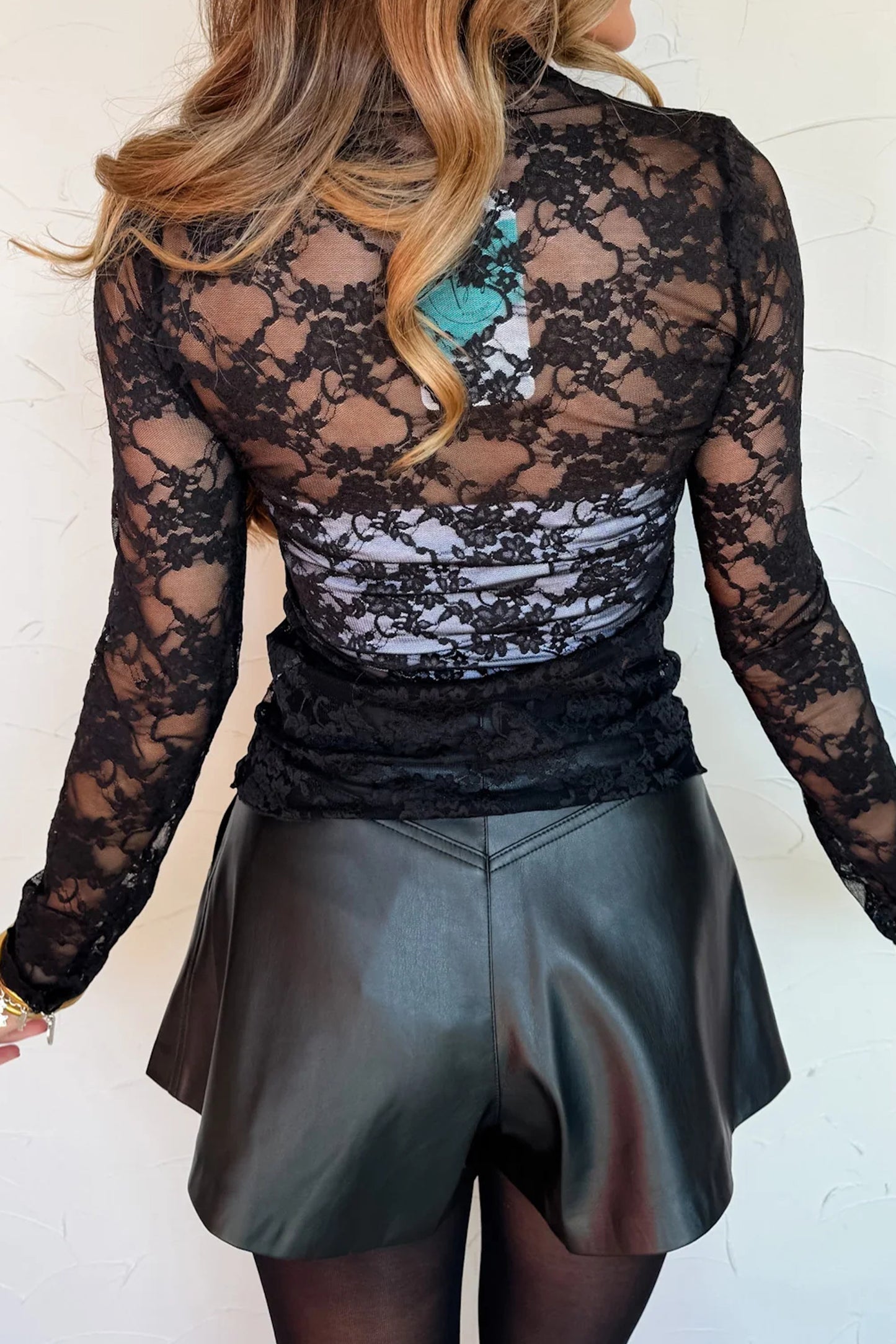 Top de manga larga de encaje floral semitransparente negro con cuello simulado y dobladillo ondulado