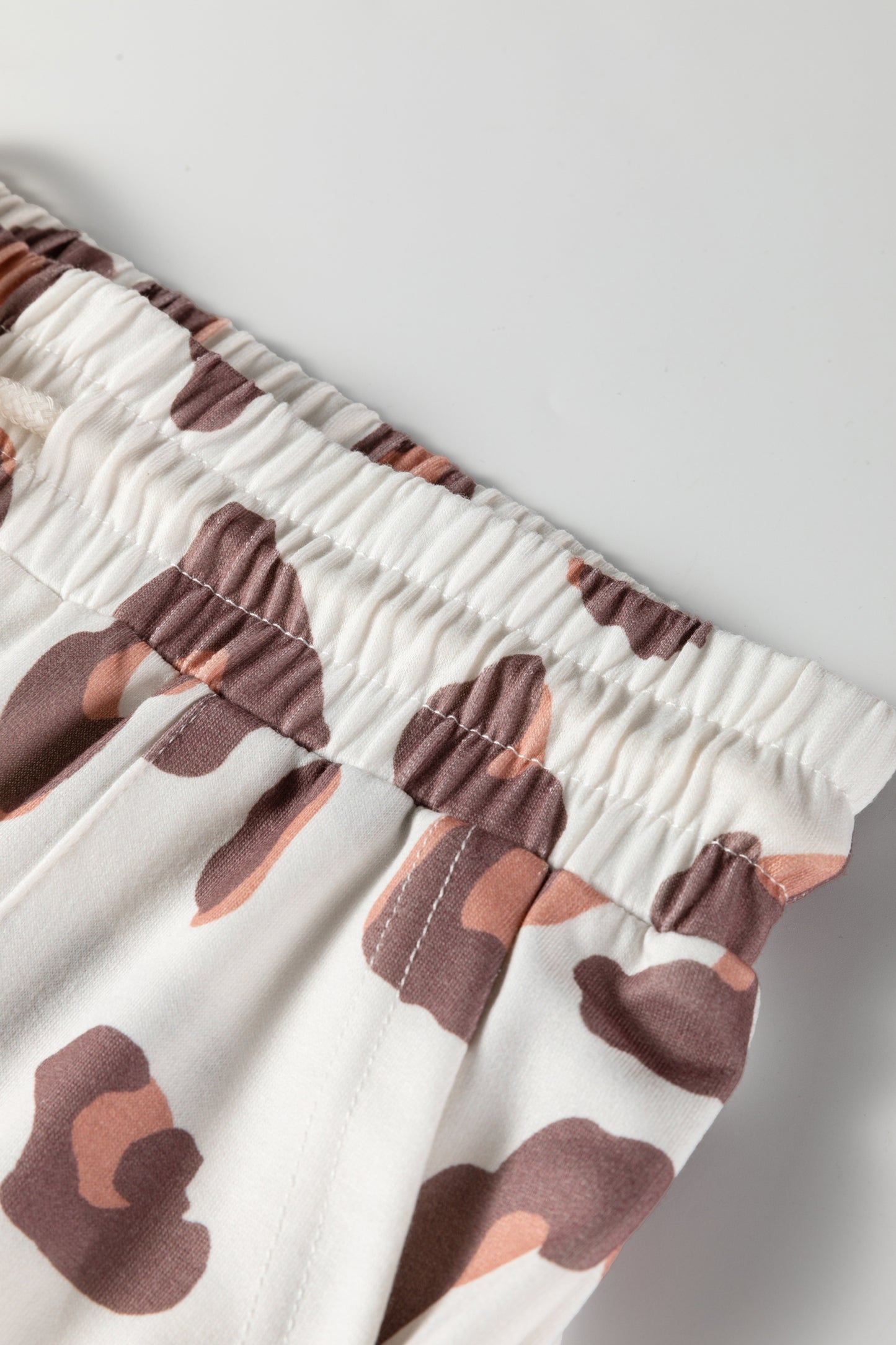Pantalones sueltos de chándal color beige con estampado de leopardo y bolsillos de parche